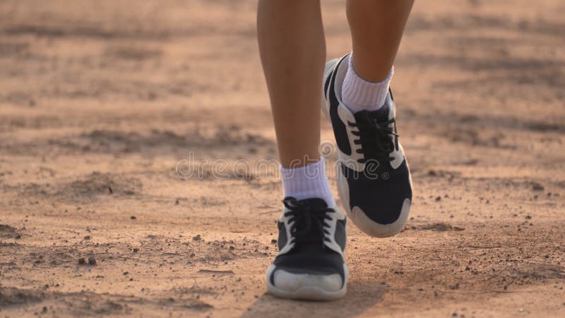 Close up leg of boy running on ground on light of sunset, kids jogging on rural countryside for good heath