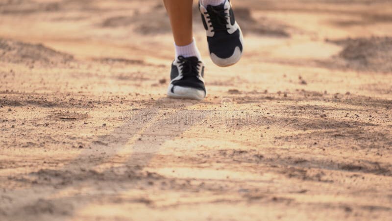 Close up leg of boy running on ground on light of sunset, kids jogging on rural countryside for good heath