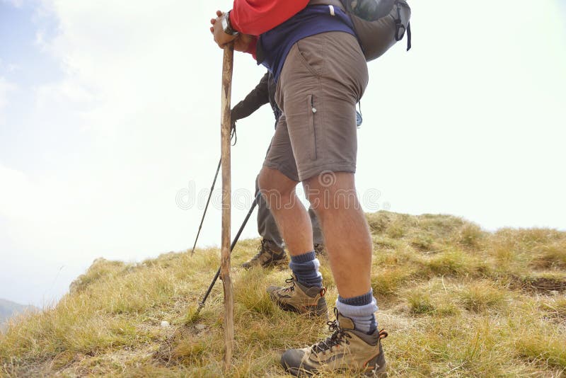 Close-up of legs of young hikers walking on the country path. Young couple trail waking. Focus on hiking shoes