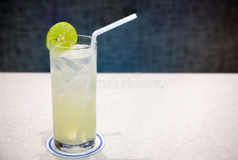 Close up lime juice glass with straw on blur background.