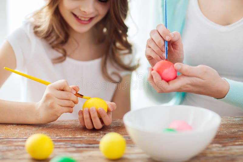 Close up of little girl and mother coloring eggs