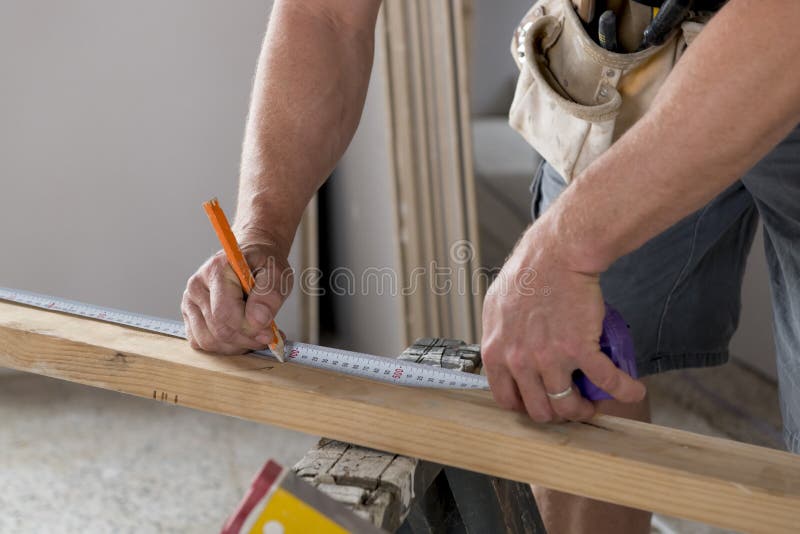Close up male constructor carpenter or builder hands detail working and measuring wood in industrial construction job concept royalty free stock photography