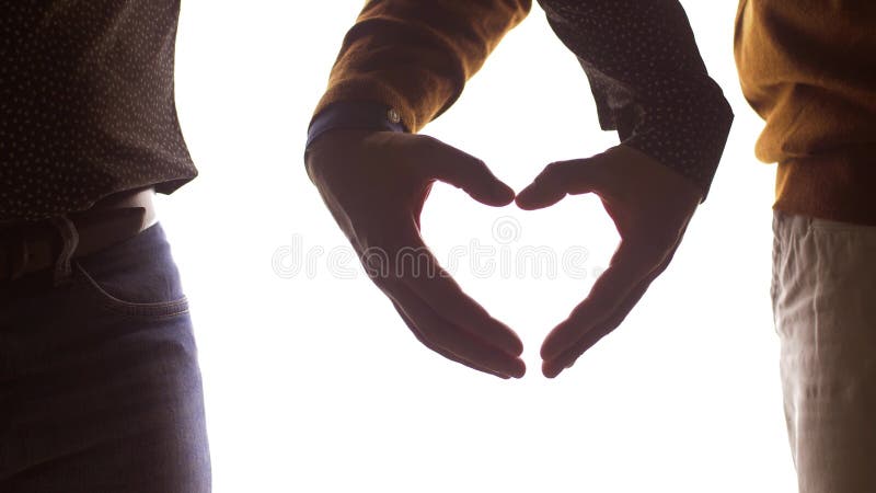 Close up of male gay couple making hand heart