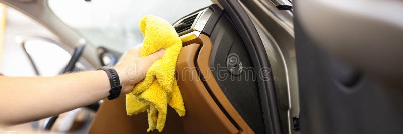 Close-up of male hand cleaning vehicle interior, cleaner washes car leather salon. Cleaning service, or self-service car wash, removing of dust concept