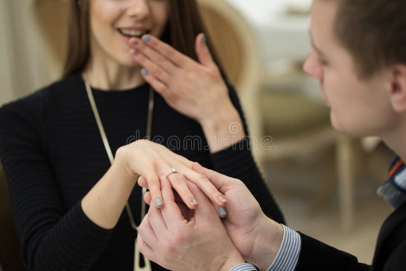 Close Up of Male Hand Inserting an Engagement Ring into a Finger. Stock