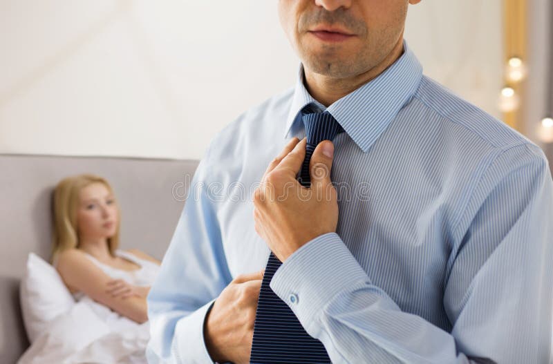 Close up of man adjusting tie on neck in bedroom