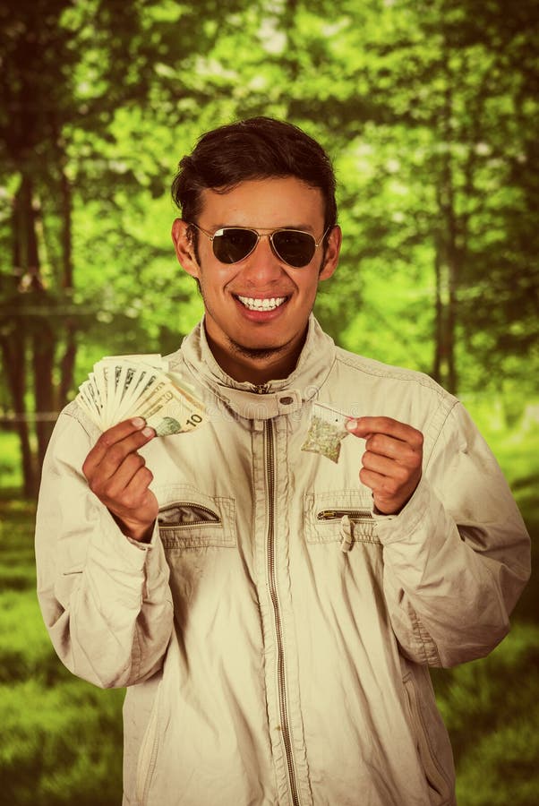 Close up of a man dealer wearing dark sunglases, and holding in his hands money and drug in his other hand, trafficking royalty free stock photos Close up of a man dealer wearing dark sunglases, and holding in his hands money and drug in his other hand, trafficking royalty free stock photos