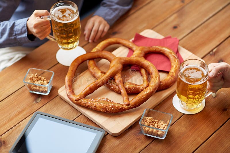 Close up of man drinking beer with pretzels at pub