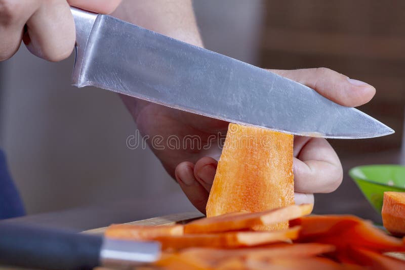Z blízka muž ruky riadok mrkva varenie veľký nôž, na veľký kusov.