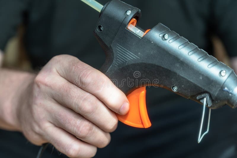 Closeup of a Man Holding a Glue Gun. a Grown Man with a Hand Tool