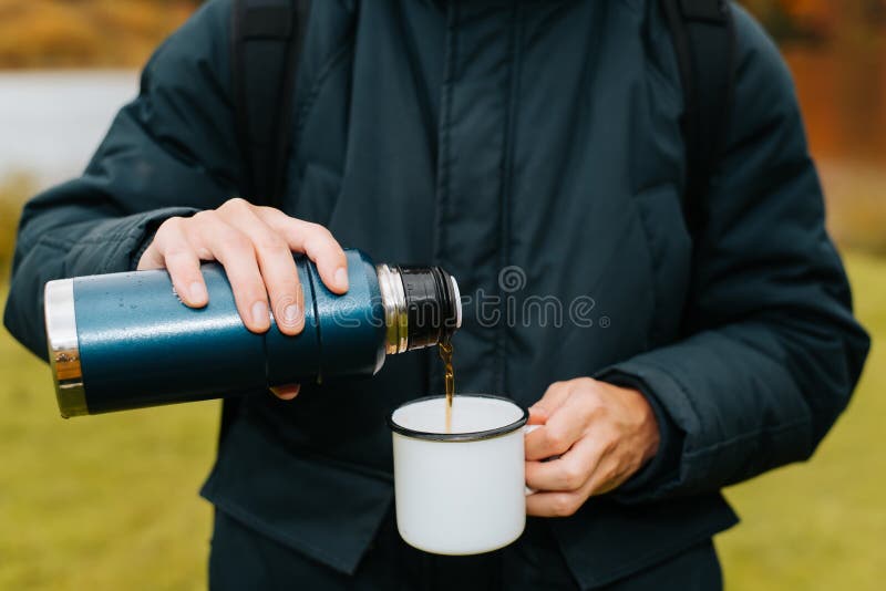Close-up of Man Holding Thermos and an Iron Mug, Pouring Hot Tea