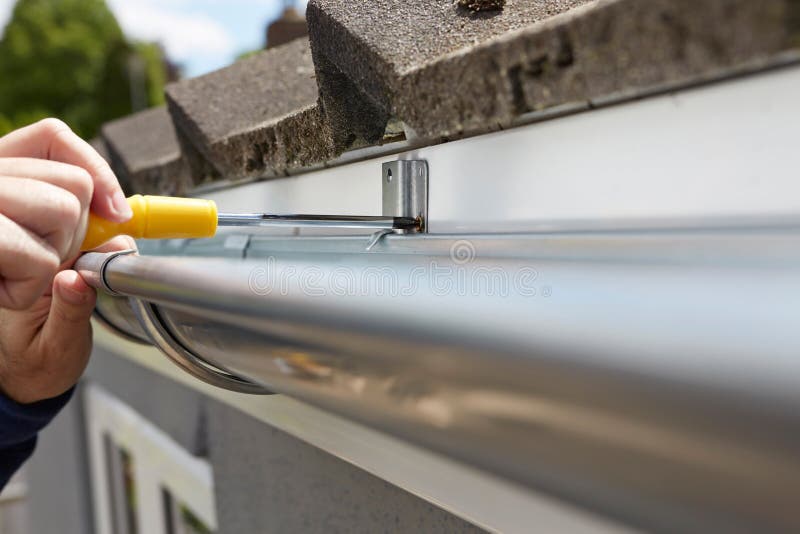 Close Up Of Man Replacing Guttering On Exterior Of House stock image