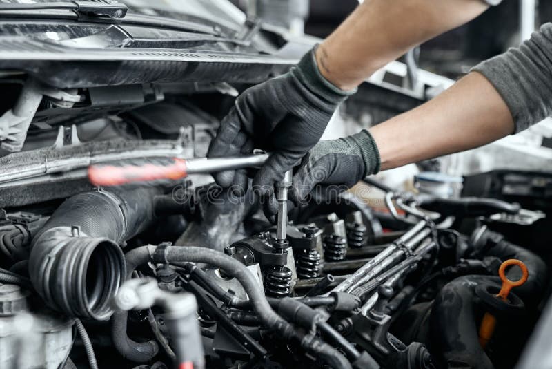 Close up of man`s hands using wrench to remove spark plugs