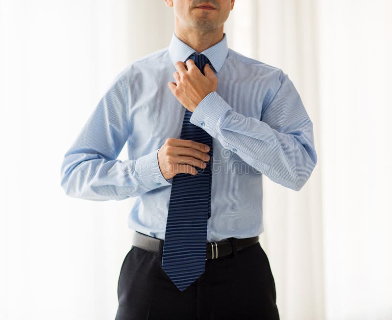 Close up of man in shirt adjusting tie on neck