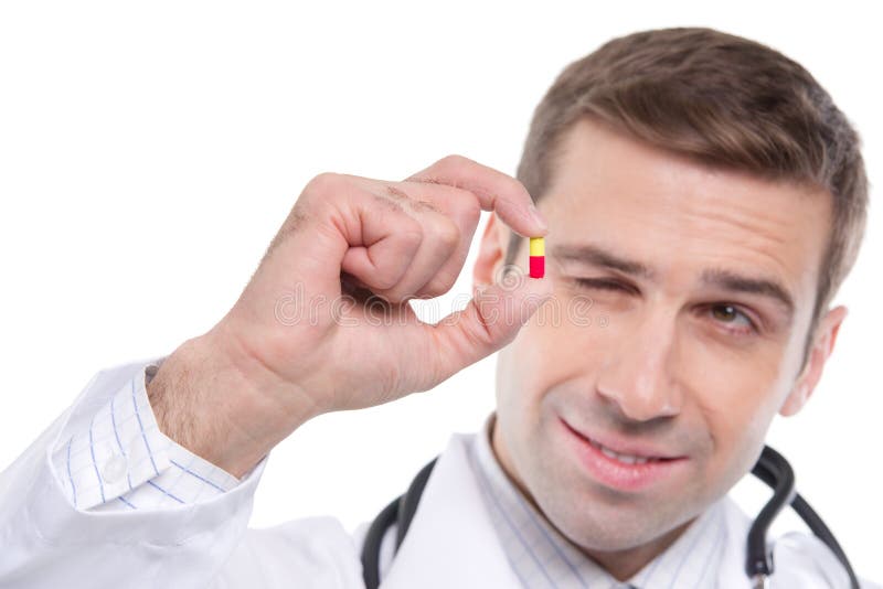 Close up of medical doctor holding small yellow-red pill