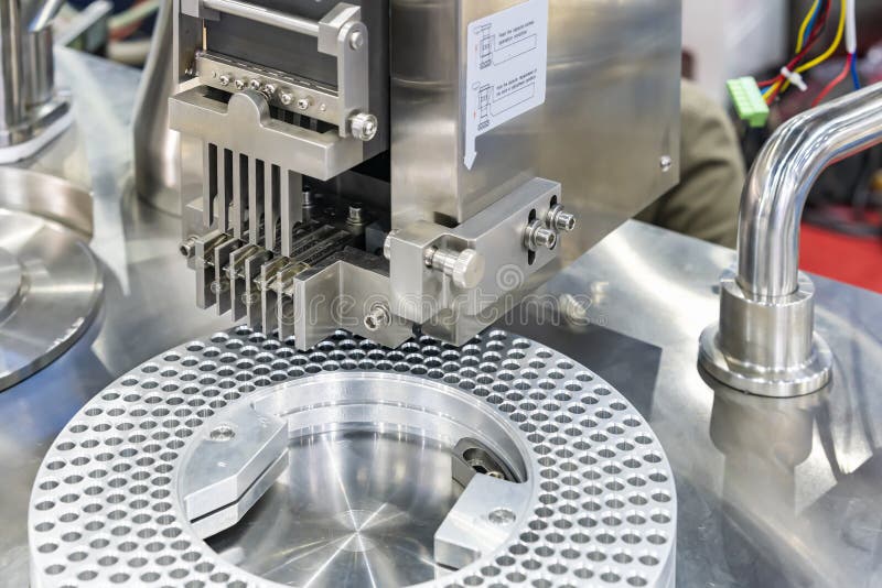 Close up medicine transparent capsule at feeding fork of automatic capsule filling machine during manufacturing process in stock images