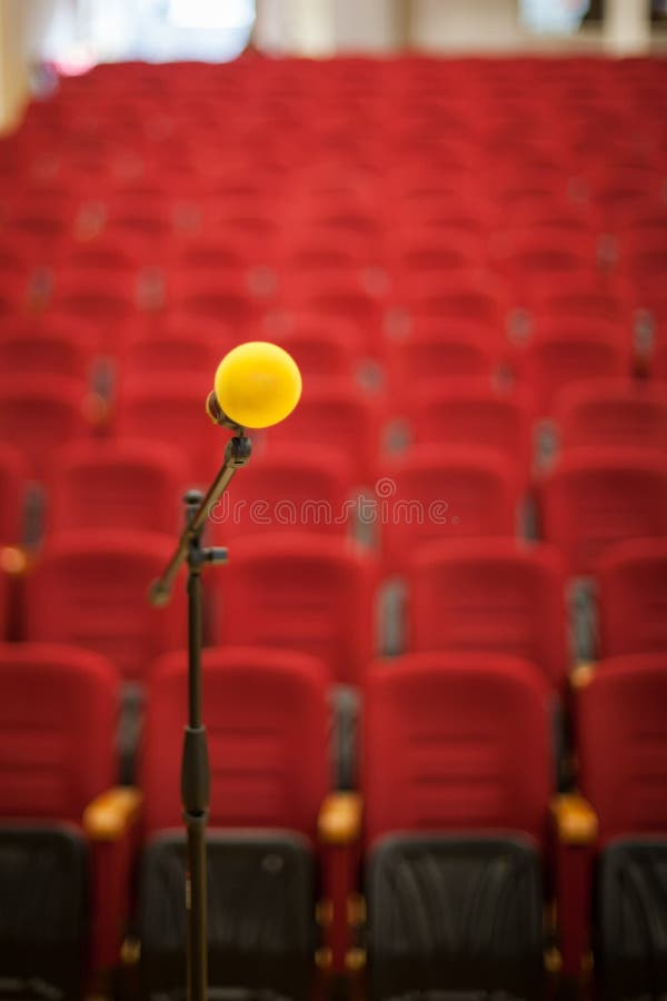 Close up of microphone in front of empty chairs hall. Before a conference, concert, seminar.