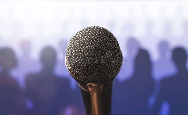 Close up of microphone in front of a silhouette audience. royalty free stock photo