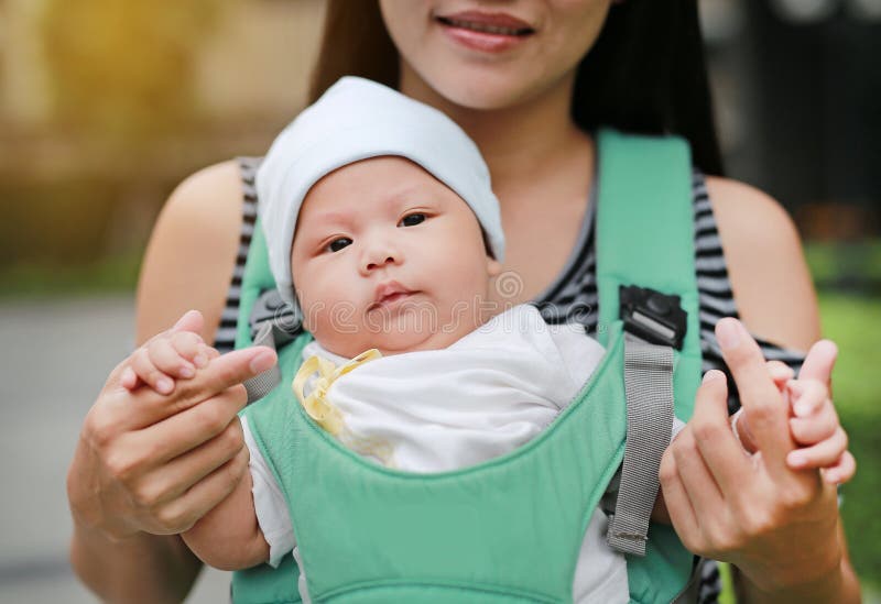 Close-up mother carrying her infant by ergonomic baby carrier stock photos Close-up mother carrying her infant by ergonomic baby carrier stock photos