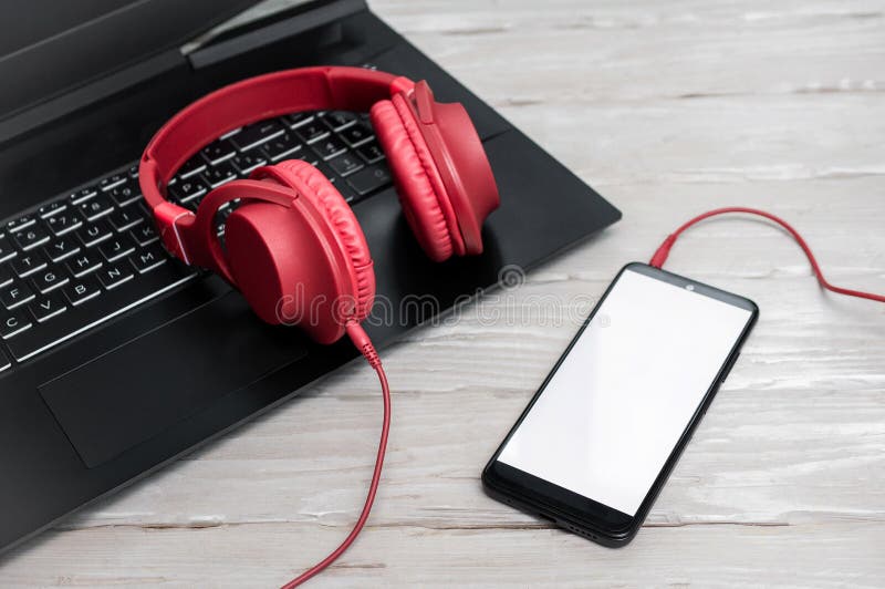 Close-up of musical red overhead headphones on a pc keyboard. Audio music headphones with laptop and with smartphone with white royalty free stock images