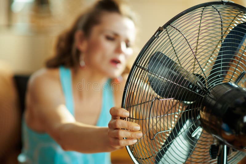Close up na dona de casa que usa o sofrimento do fã do calor do verão