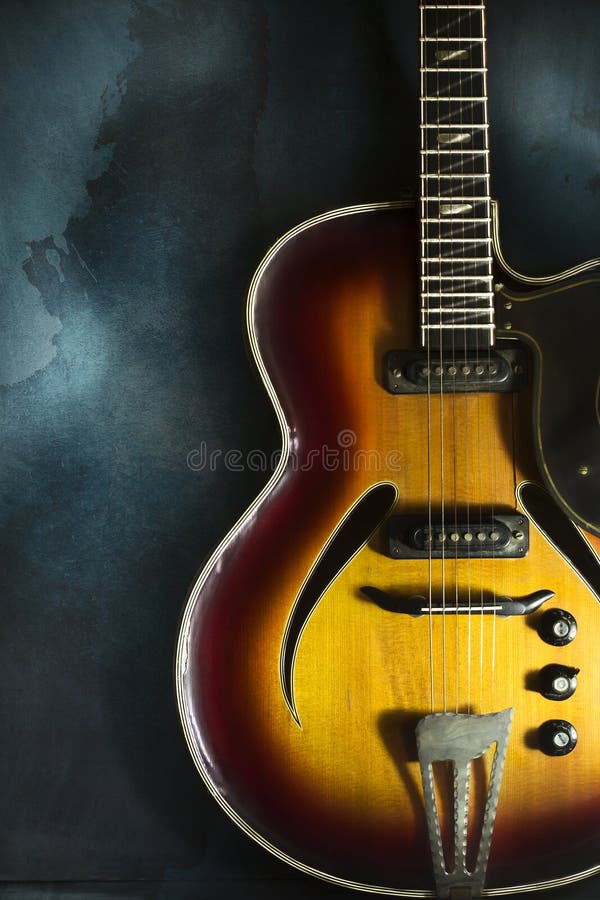 Closeup of Old Electric Jazz Guitar on a Dark Blue Background Stock