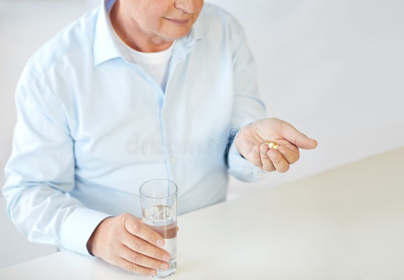 Close up of old man with pills and water glass