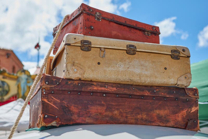 Close-up of old vintage travel suitcases fastened to the roof of a car with a rope and in the background a lovely blue sky with cl