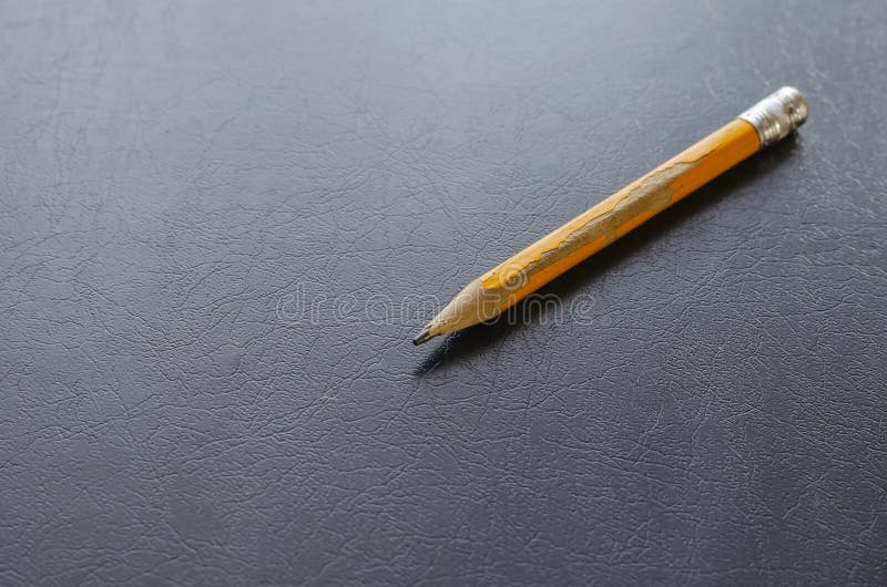 Close-up of an old yellow wooden pencil on black table