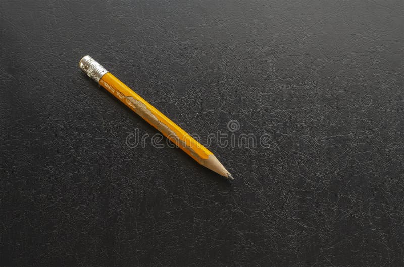 Close-up of an old yellow wooden pencil on black table