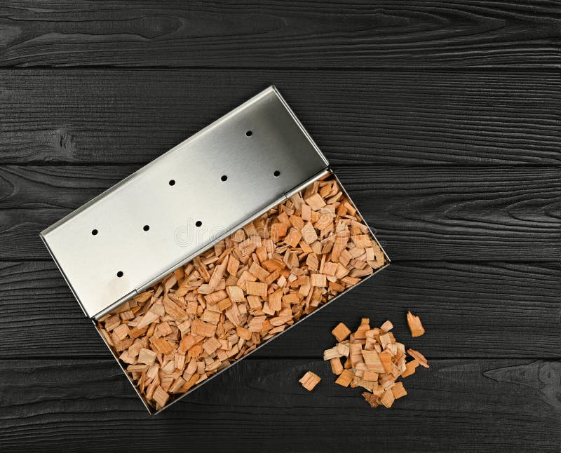 Metal smoker box with wood chips on table