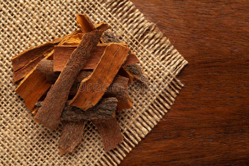 Close-up of Organic cinnamon  Cinnamomum Verum or dalchini on the wooden top background and jute mat. Pile of Indian Aromatic Sp