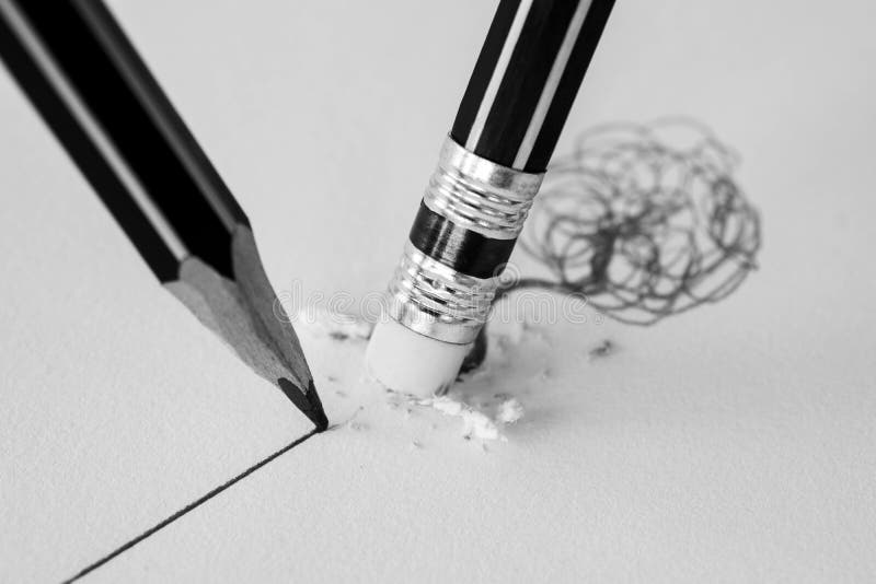 Close up of a pencil eraser removing a crooked line and the close up of a sharpened pencil writing a straight line. stock photography