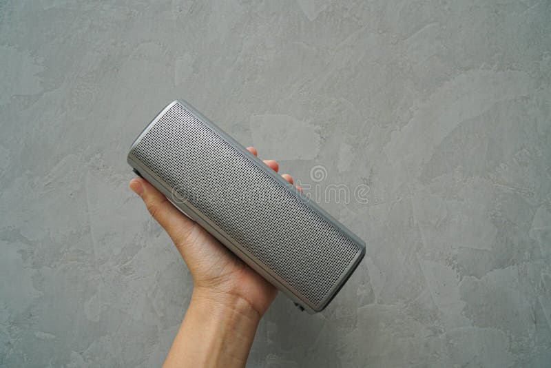 People hold Bluetooth speaker in hand for music connection with loft wall background stock photography