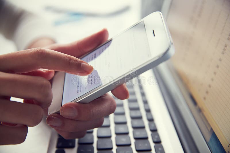 Close Up Of Person At Laptop Using Mobile Phone