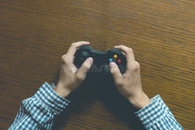 Close up person`s hands playng video game isolated on wooden table concept stock photo Close up person`s hands playng video game isolated on wooden table concept stock photo