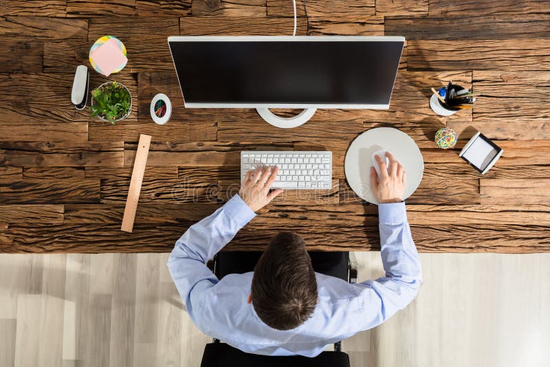 Close-up Of A Person Using Computer On Office Wooden Desk