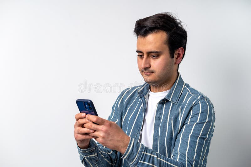 Close up photo of a brown skinned young adult model, texting with friends on social media with smartphone on isolated white background.