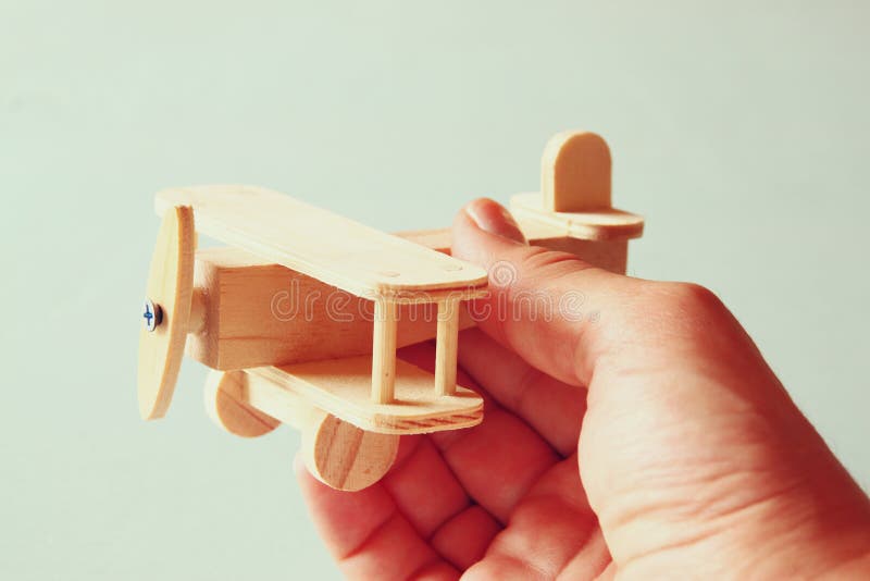Close up photo of man's hand holding wooden toy airplane over wooden background. filtered image. aspiration and simplicity concept stock photography Close up photo of man's hand holding wooden toy airplane over wooden background. filtered image. aspiration and simplicity concept stock photography