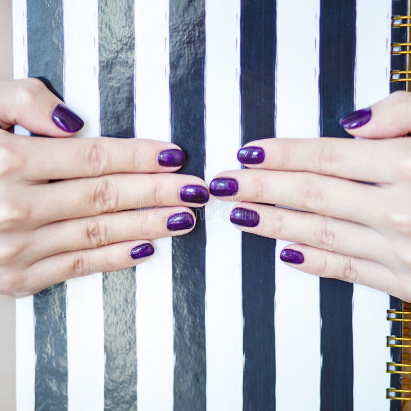 Close-up photo of manicured woman`s hands hold an elegant notebook with black and white strips