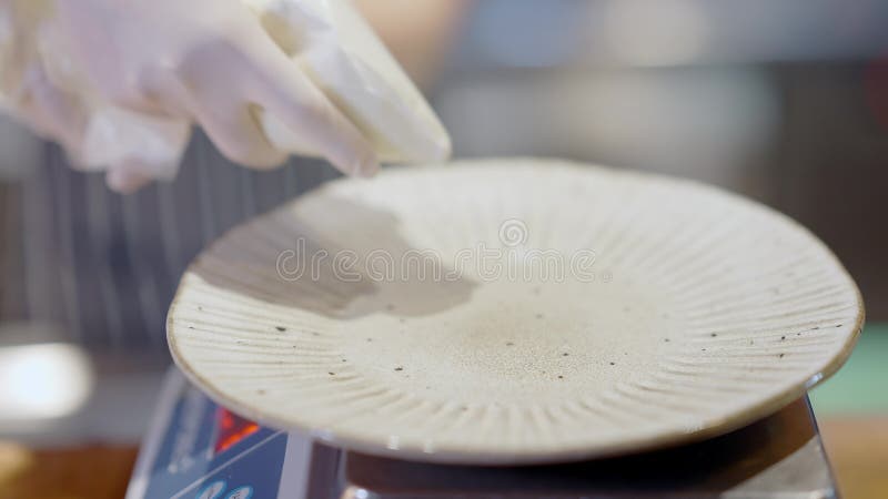 Close-up of plate with female Caucasian hands in gloves pouring mayonnaise. Unrecognizable young cook preparing dish in