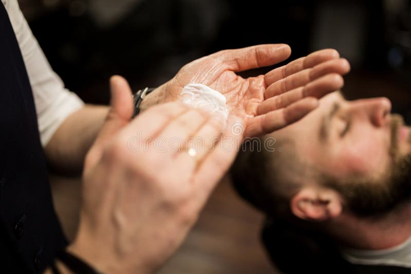 Barber's hands spray the little boy's hair with a spray gun. Stock