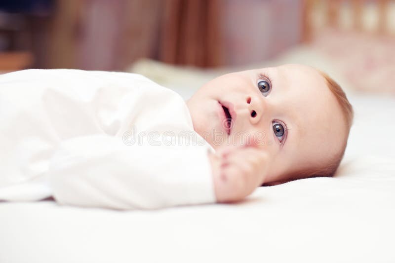 Close-up portrait of beautiful baby lying on bed