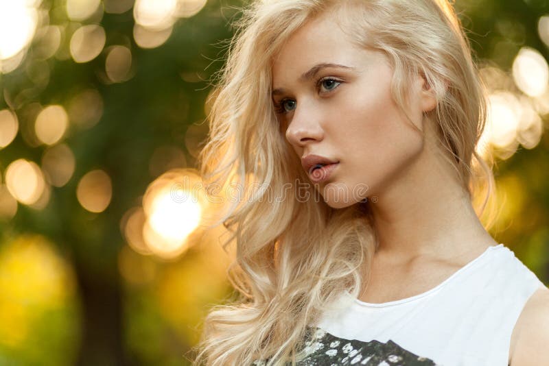 Close up portrait of a beautiful blonde woman with curly blonde hair in the park