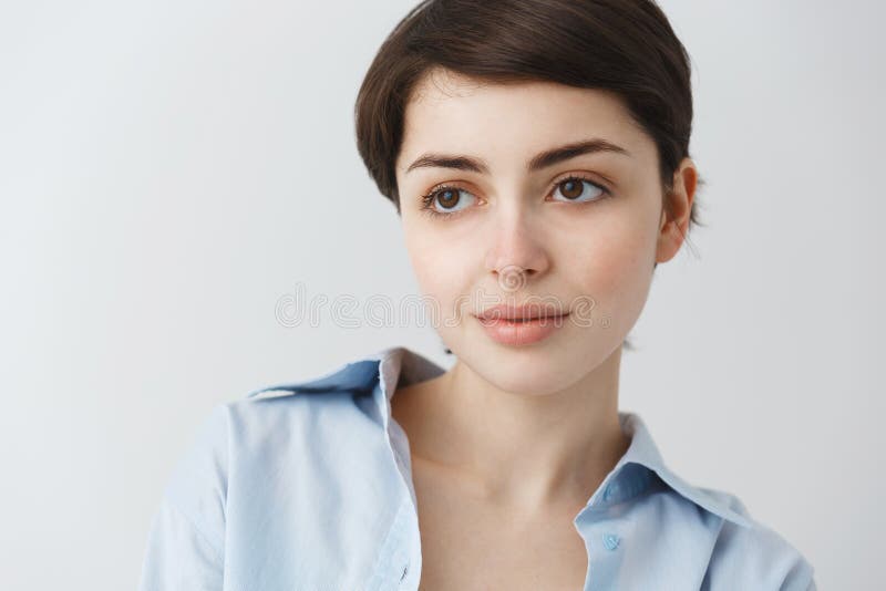 Close up portrait of beautiful caucasian girl with short dark hair and big brown eyes looking aside, smiling gently with