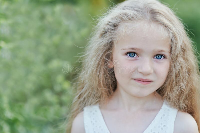 Close up portrait of beautiful little girl with blonde long hair and big blue eyes