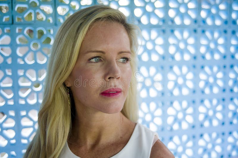 Close up portrait of beautiful and relaxed Caucasian blond woman with blue eyes looking away on a blue pattern background