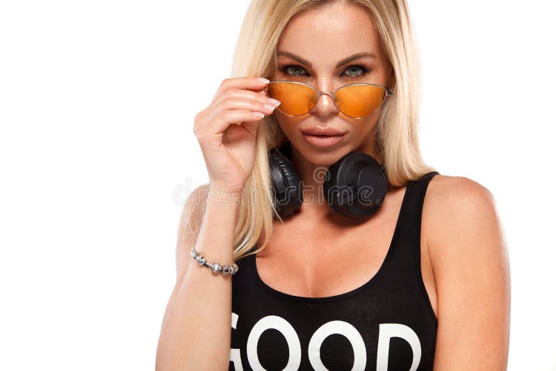 Close-up portrait of beautiful blonde DJ woman on white background in studio wearing headphones.