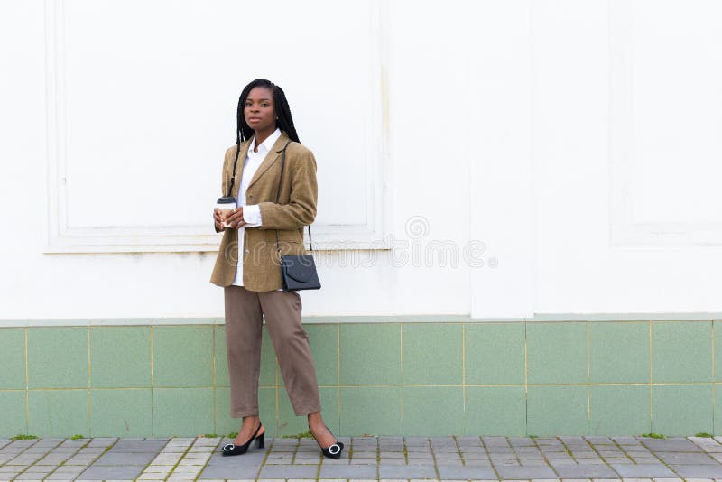 Close up portrait of a beautiful young african american woman with pigtails hairstyle in a business suit and white blouse walks