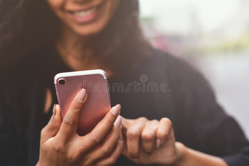 Closeup image of a beautiful mixed race woman holding, using and looking at smart phone. royalty free stock photo Closeup image of a beautiful mixed race woman holding, using and looking at smart phone. royalty free stock photo